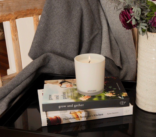 Apotheke Brooklyn Candle burning with a few books in the photo.