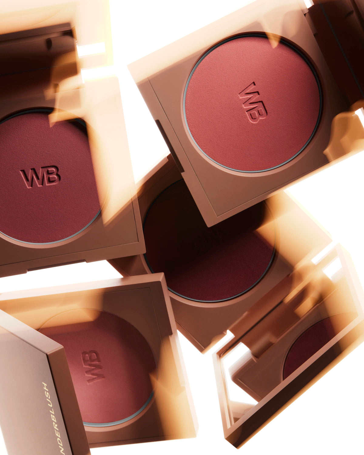 Lifestyle image of 4 Wonderblush Blush palettes floating or falling and illumitated by a warm light..