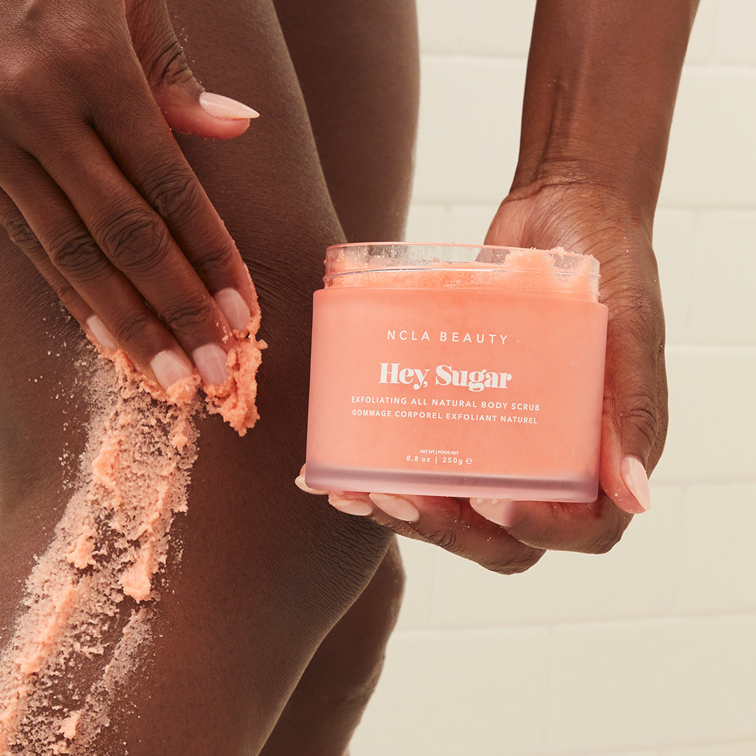 A woman using NCLA's Hey, Sugar Scrub on her legs.