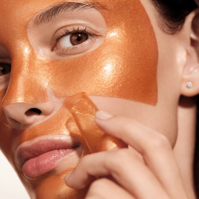 Close up of models skin using Augustinus Bader Hydrogel Mask applying it to her face.