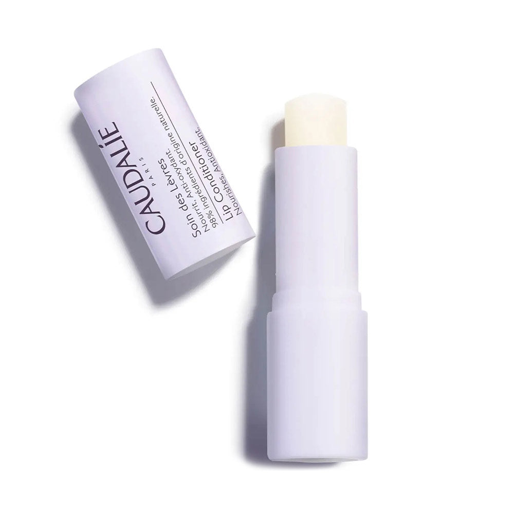 A stick of Caudalie lip conditioner in a white tube with purple and black text.
