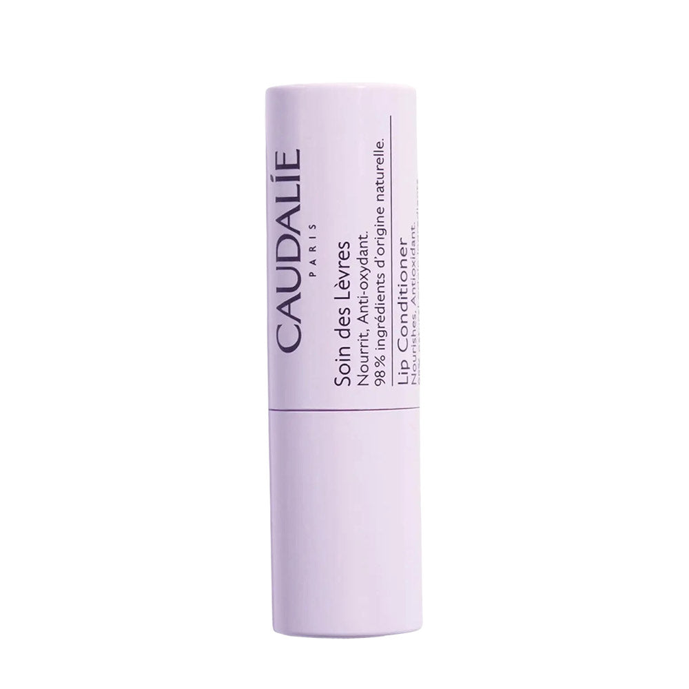 A stick of Caudalie lip conditioner in a white tube with purple and black text.