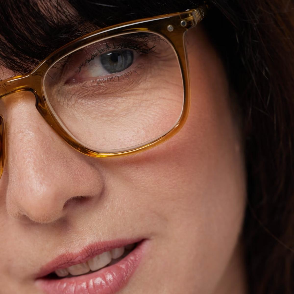 Close-up of a person wearing golden green-framed glasses with a blurred background
