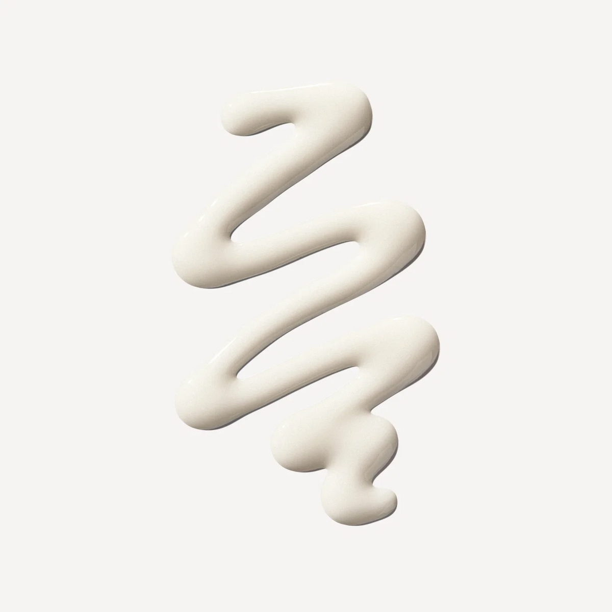 A thick, creamy off-white cosmetic or substance is shown in a zigzag squiggle on a plain light gray background.