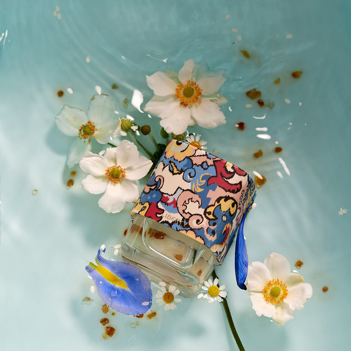 Tudor perfume bottle with flowers in water on a light blue background