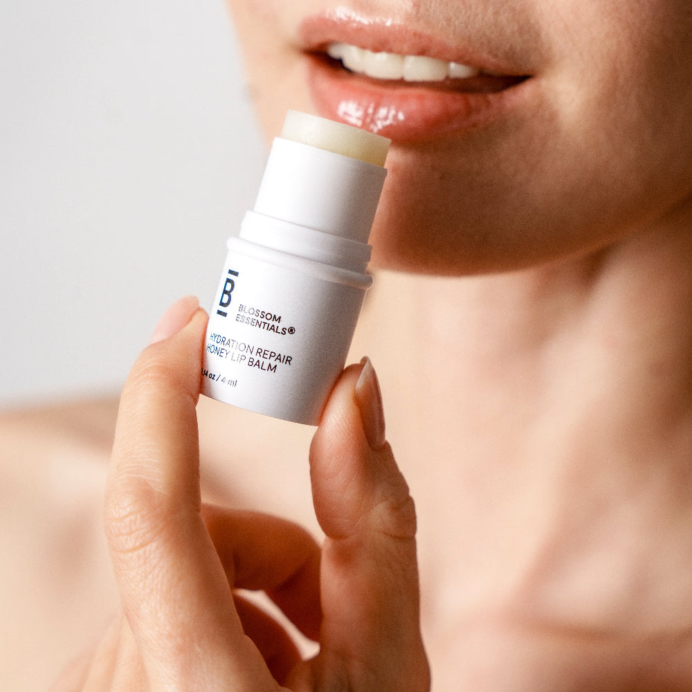 Person applying a lip balm stick to their lips with a neutral background