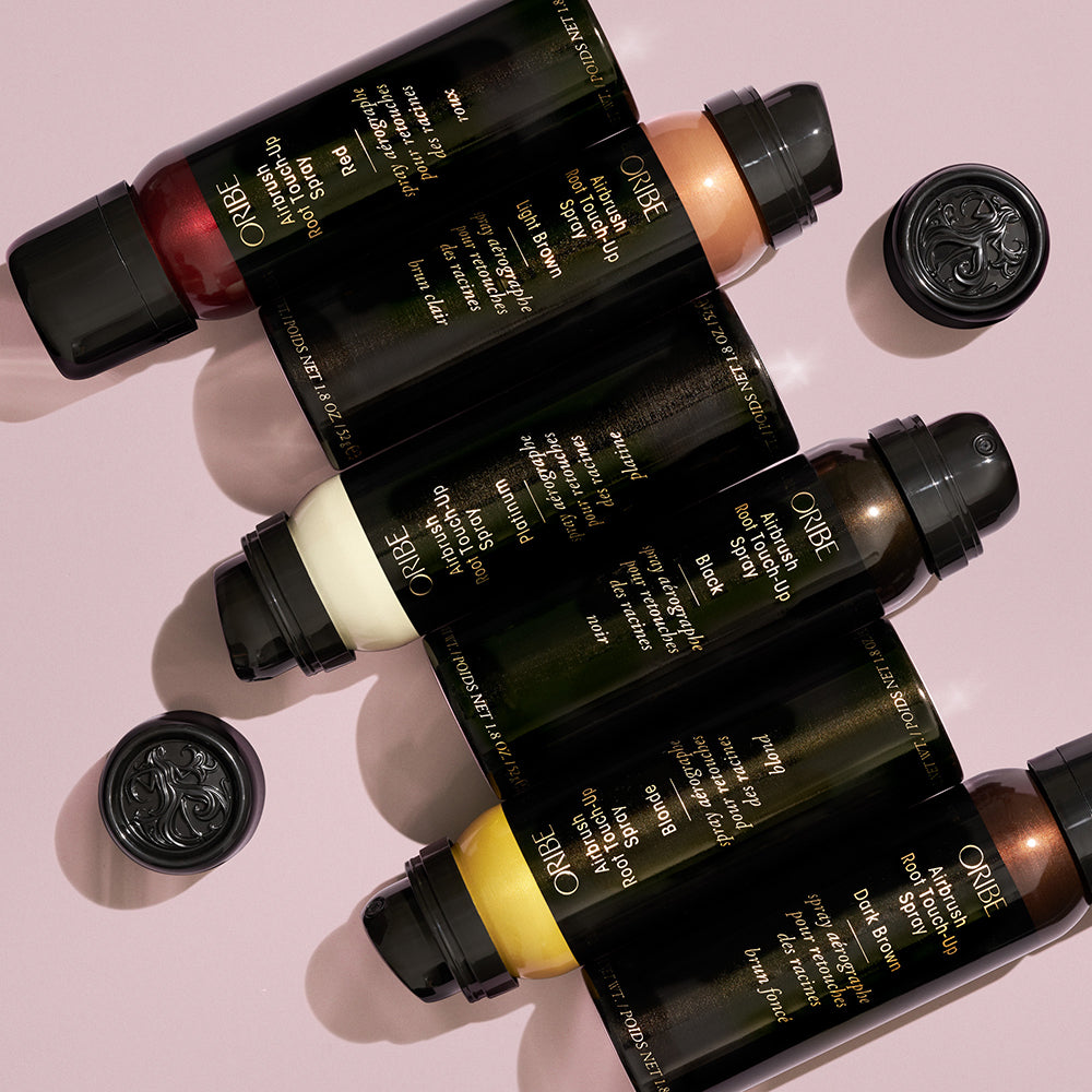 various colors of the Oribe Airbrush touch up sprays lined up in a diagonal next to each other.
