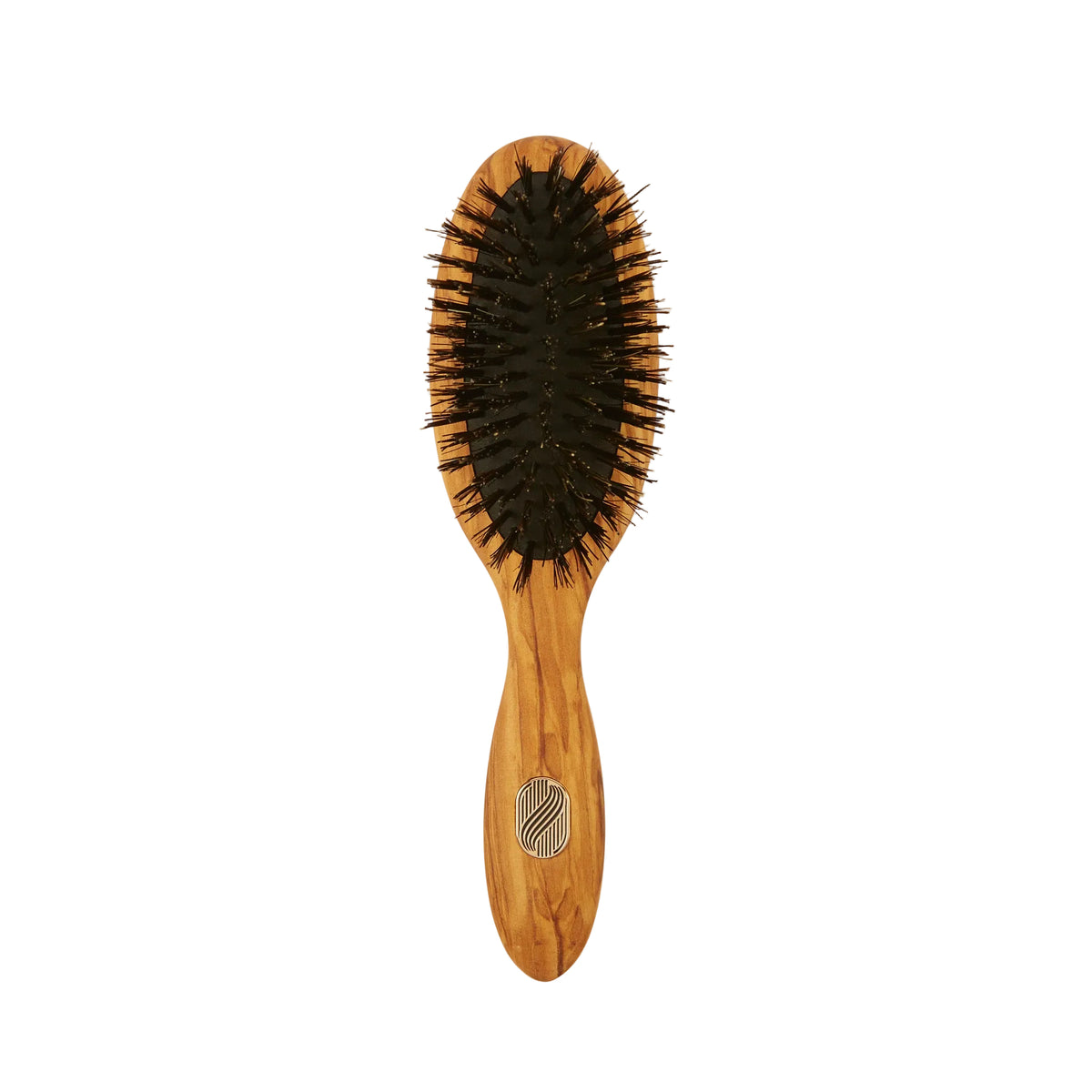 An oval-shaped wooden hairbrush with black bristles, featuring a light brown wood handle with a silver metal logo emblem, set against a plain off-white background.