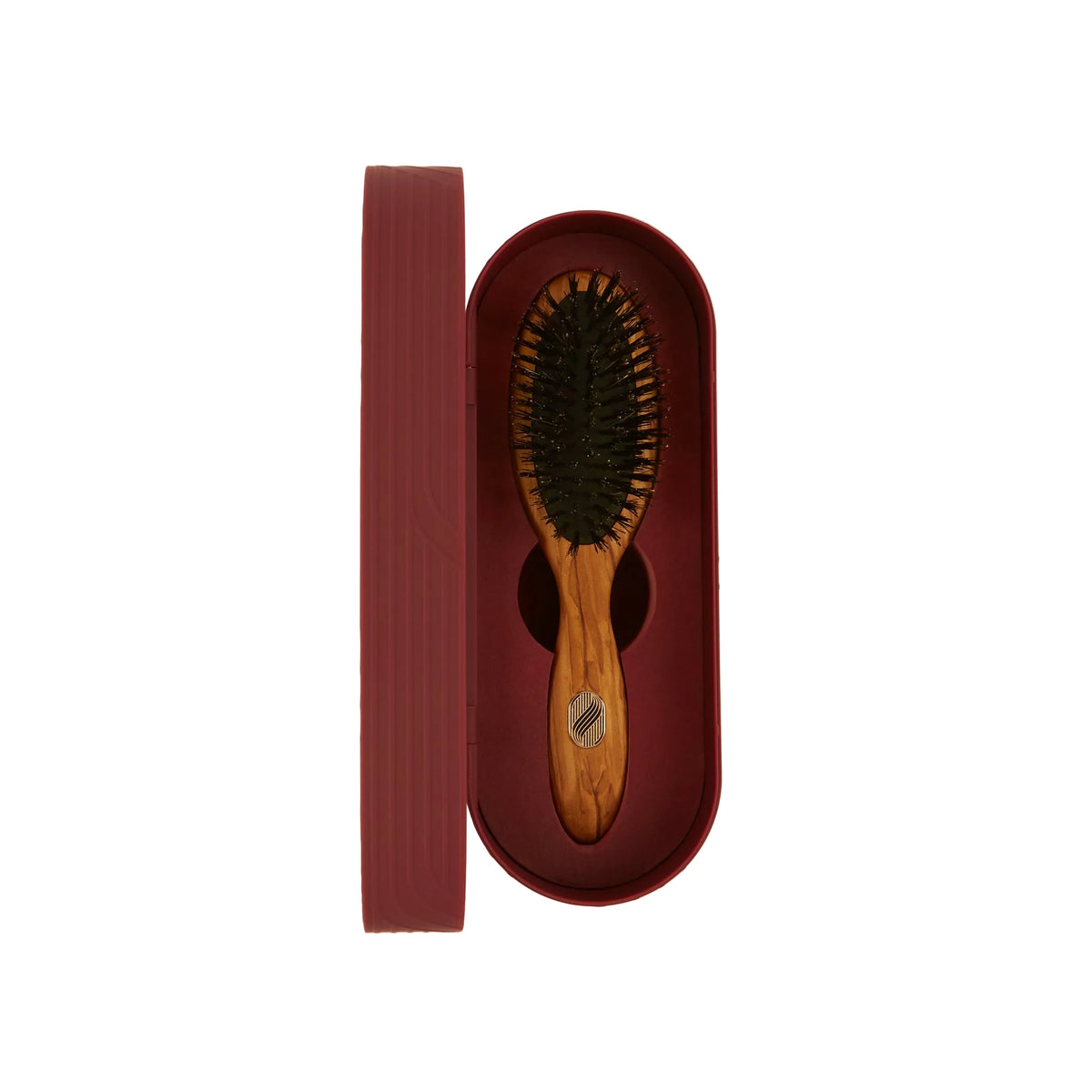 Wooden hairbrush in a red leather case on a beige background