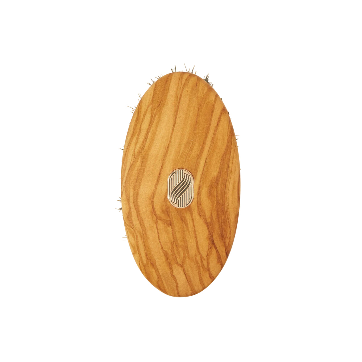 An oval wooden hairbrush with a natural olive wood grain finish and a small silver metal logo in the center, shown against a plain off-white background.