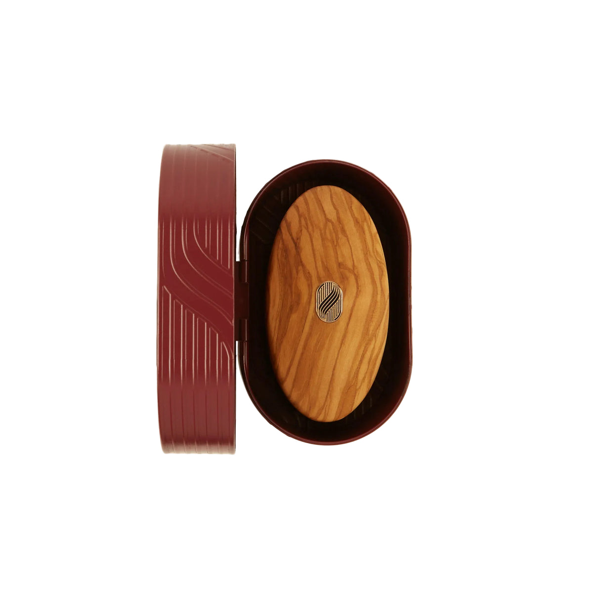 An oval wooden box shown open on a light cream background, with a dark reddish-brown outer lid leaning beside it and a natural wood insert in the center featuring a small silver geometric emblem.