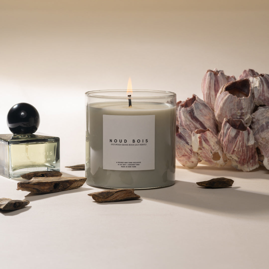 Candle labeled 'Noud Bois' with decorative elements on a neutral background