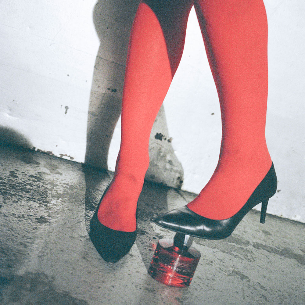 Cherry Punk - Extrait de Parfum under a foot in high heels on a rugged concrete surface