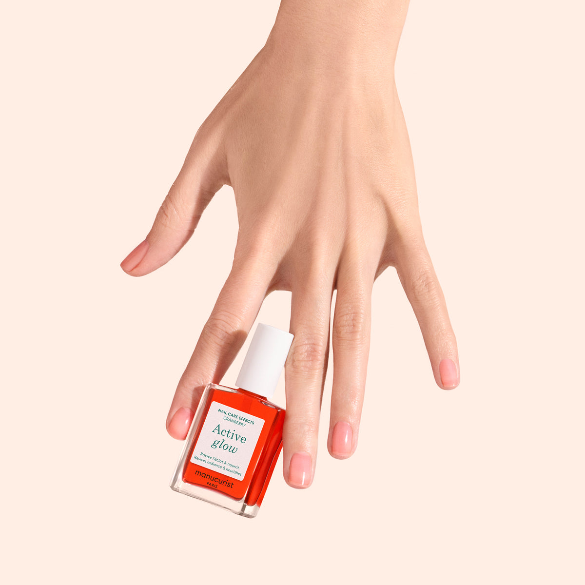 Light hand wearing and carrying Manucurist Active Glow in Cranberry 