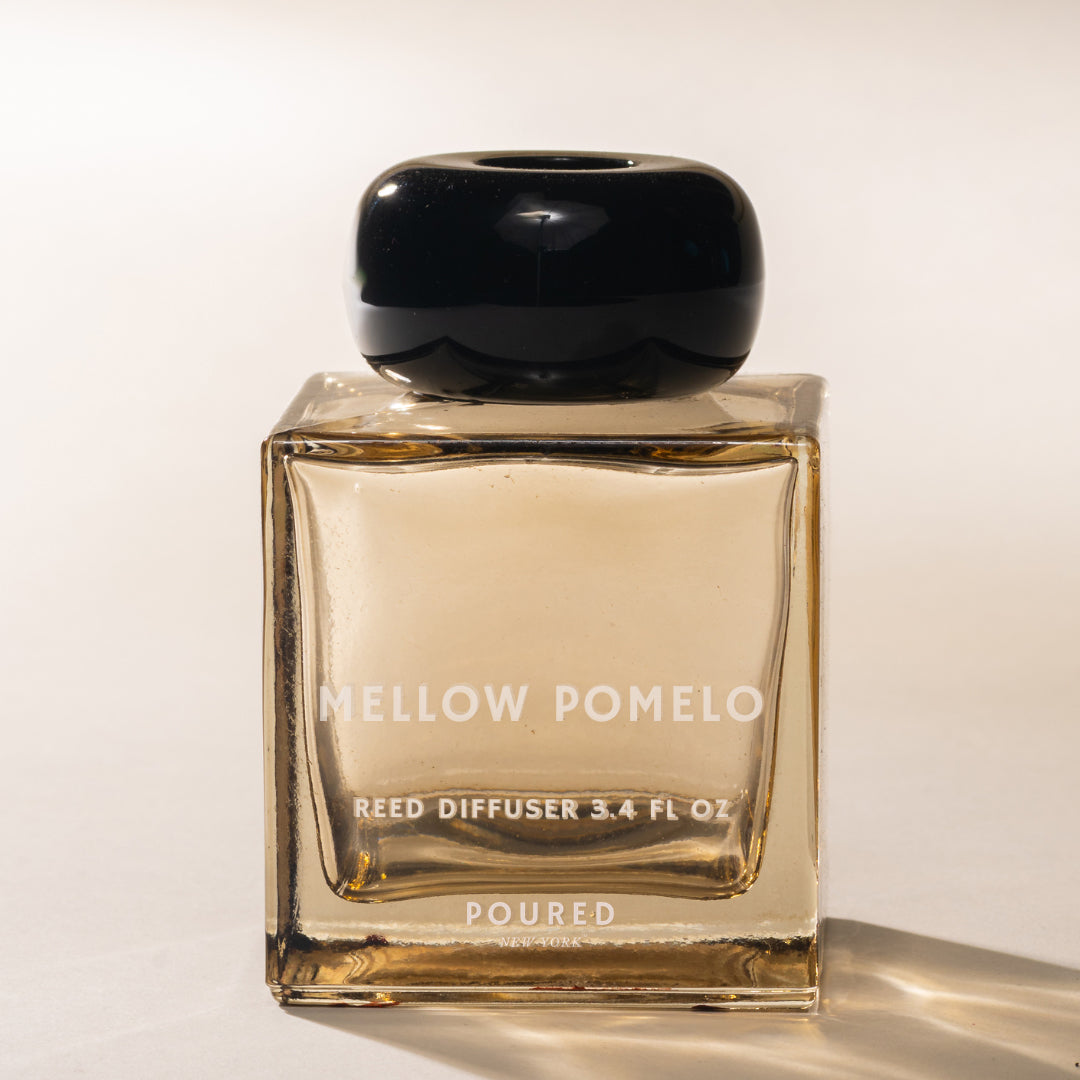 Reed diffuser bottle labeled 'Mellow Pomelo' on a white background