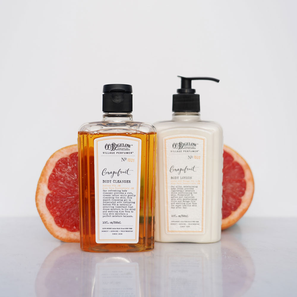 Two bottles of Grapefruit Body Cleanser and Lotion on a white background with grapefruit slices 