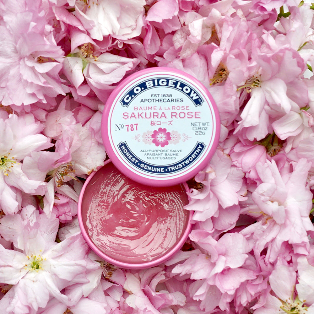 Sakura Rose Salve Tin on a bed of pink flowers.