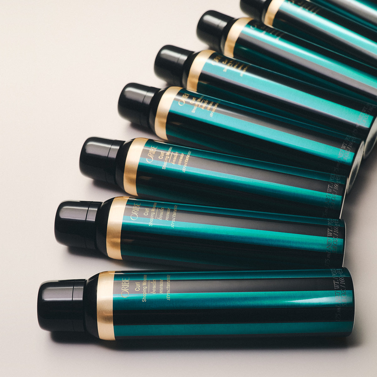 Multiple green hair care products with black caps on a light gray background