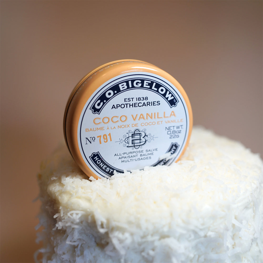 C.O. Bigelow Coco Vanilla Salve on top of a Cake in front of a tan background.