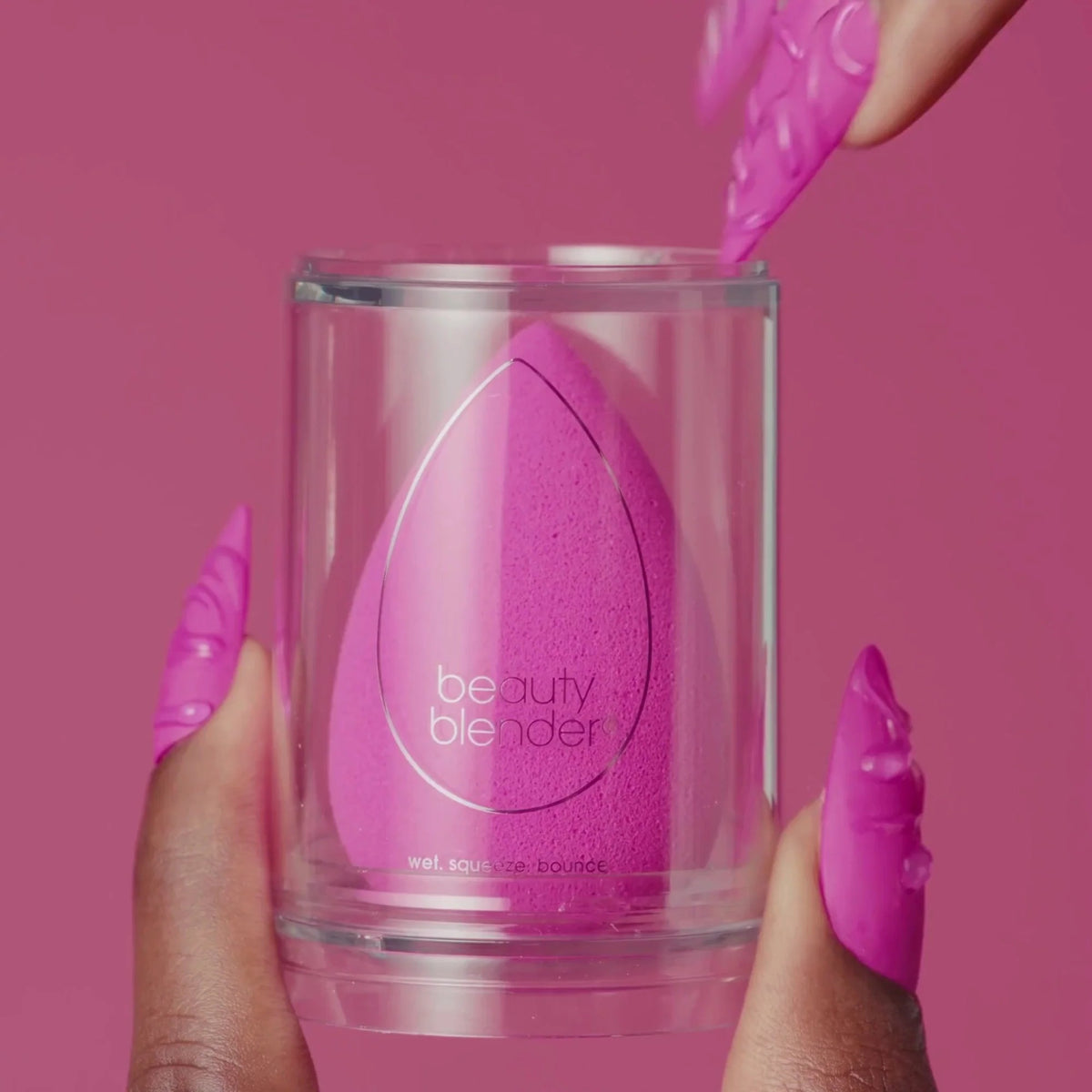 Pink beauty blender in a clear container against a pink background