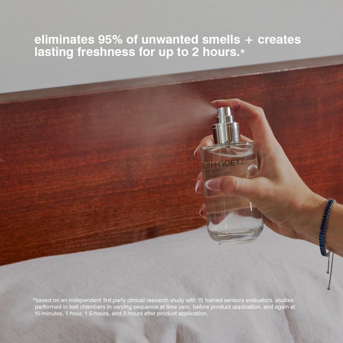 Hand holding a spray bottle with text about eliminating smells and creating freshness.