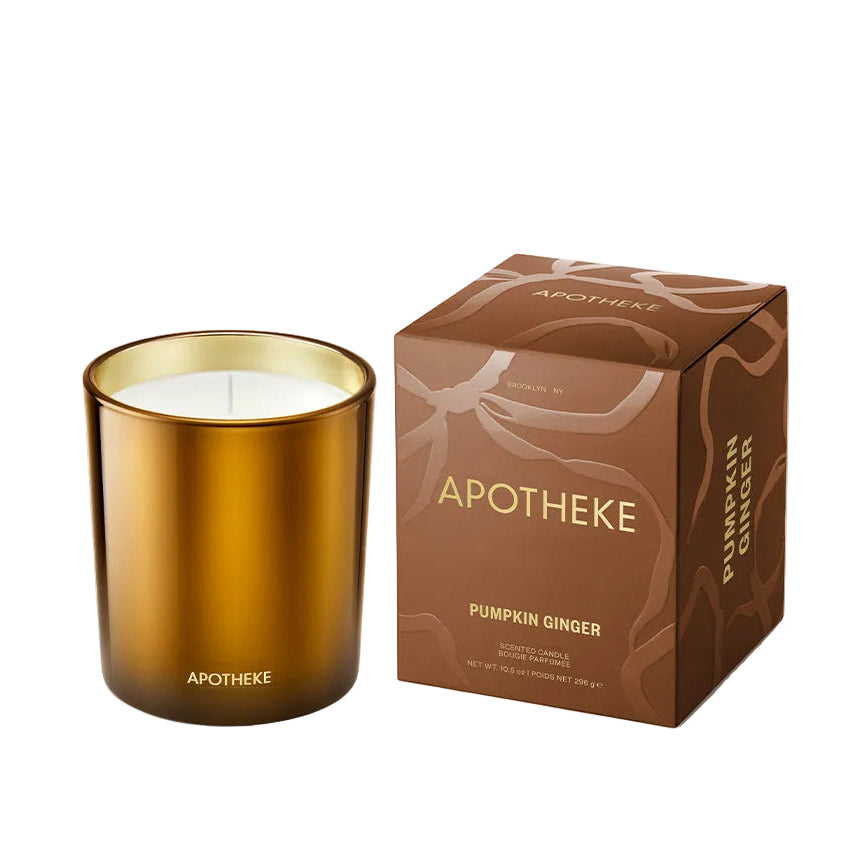 An amber glass jar candle with white wax next to its brown cardboard packaging box, both featuring the brand name 'APOTHEKE' and the scent 'Pumpkin Ginger' on a clean white background.
