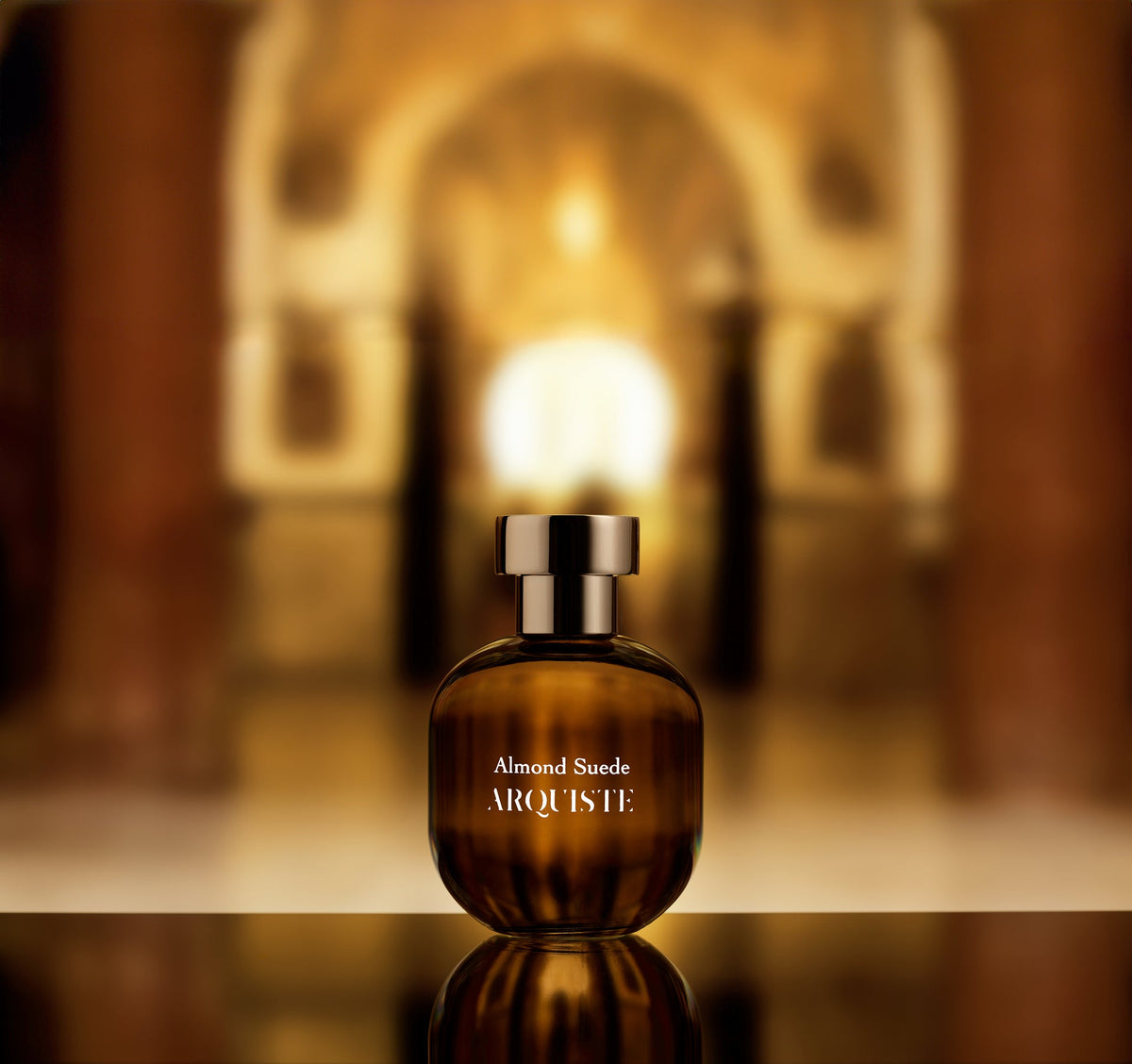 Almond Suede perfume bottle in front of a blurry background