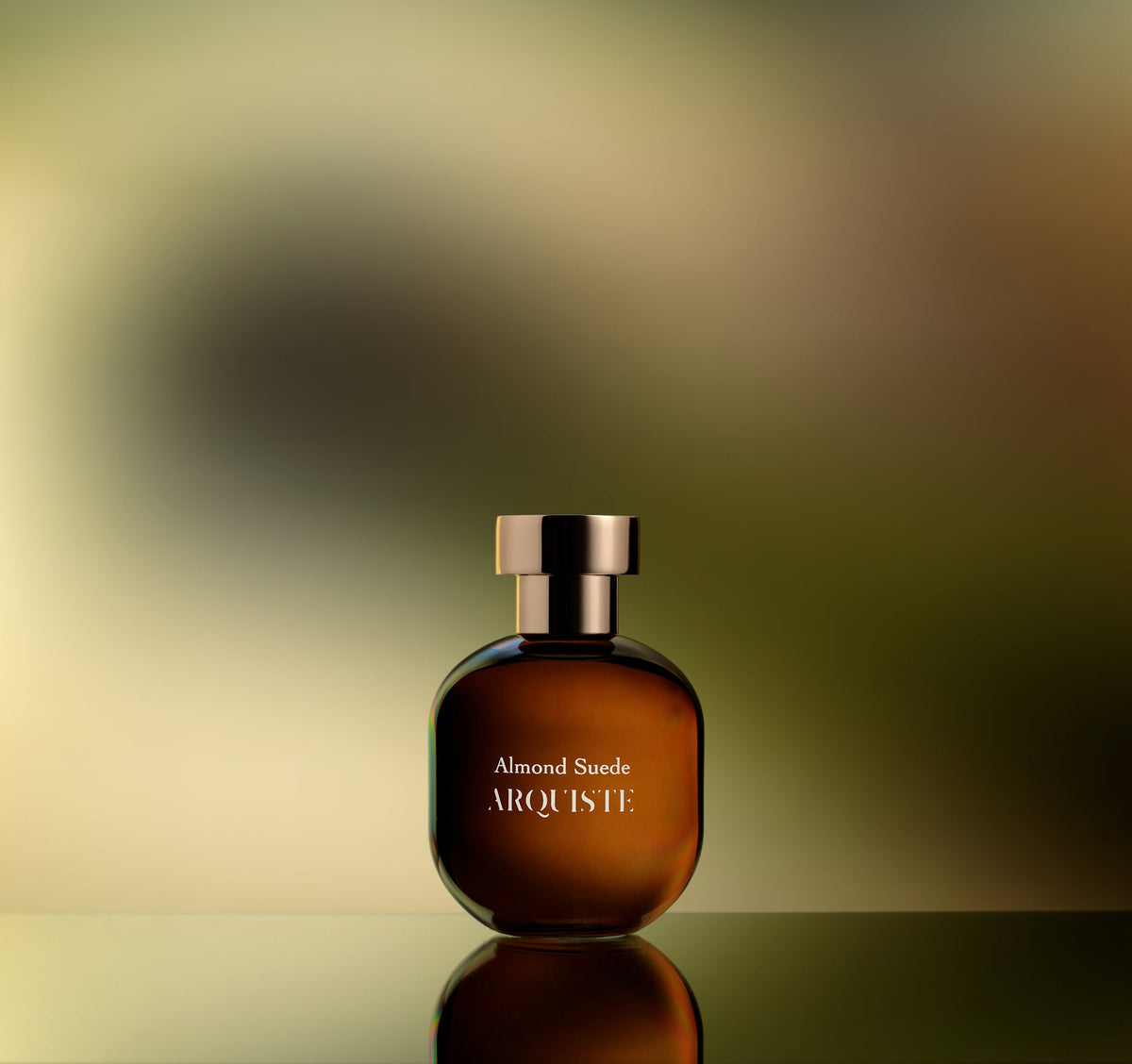 Almond Suede perfume bottle in front of a blurry background