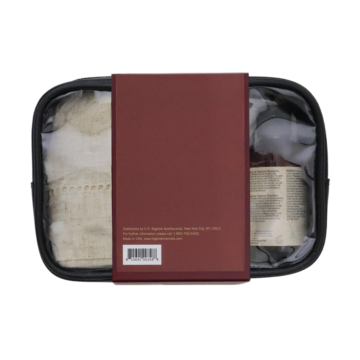 A black zippered travel pouch with a burgundy paper sleeve wrapped around the center, showing a beige woven textile and a folded brown item inside on a white background.