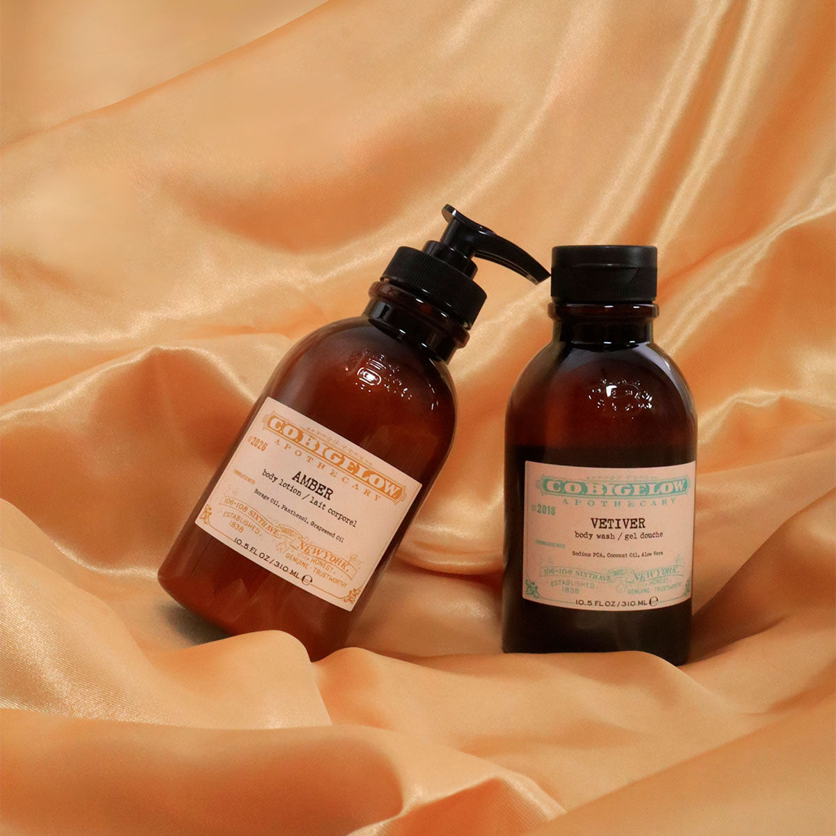 C.O. Bigelow Amber Body Lotion and C.O. Bigelow Vetiver Body Wash on top of draped silk. 