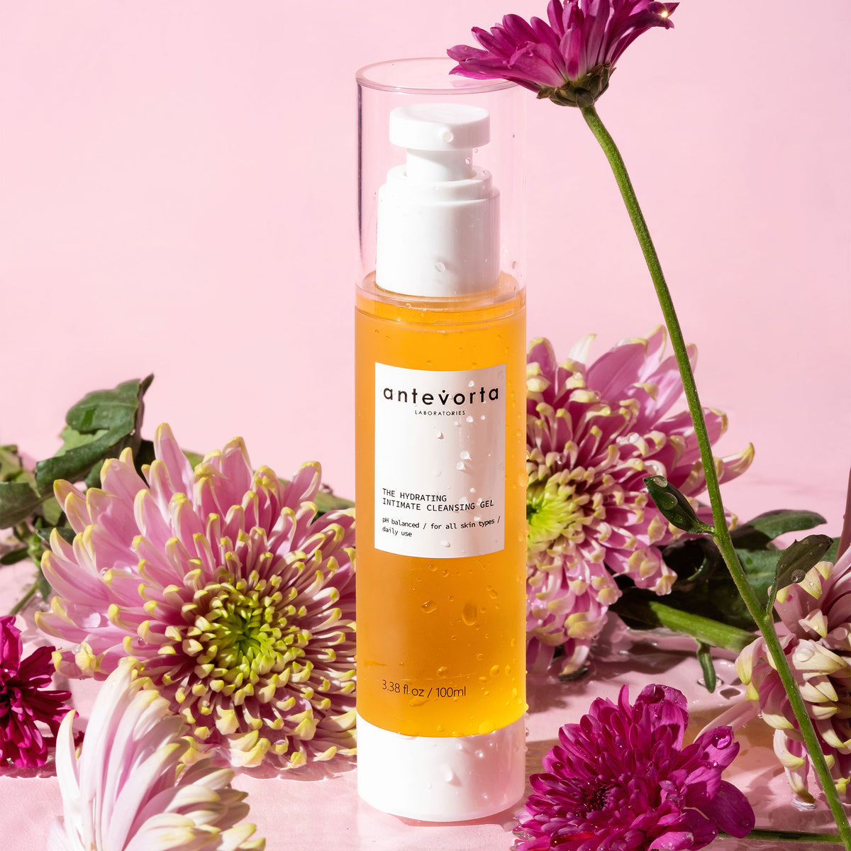 Yellow bottle surrounded by flowers on a pink background 