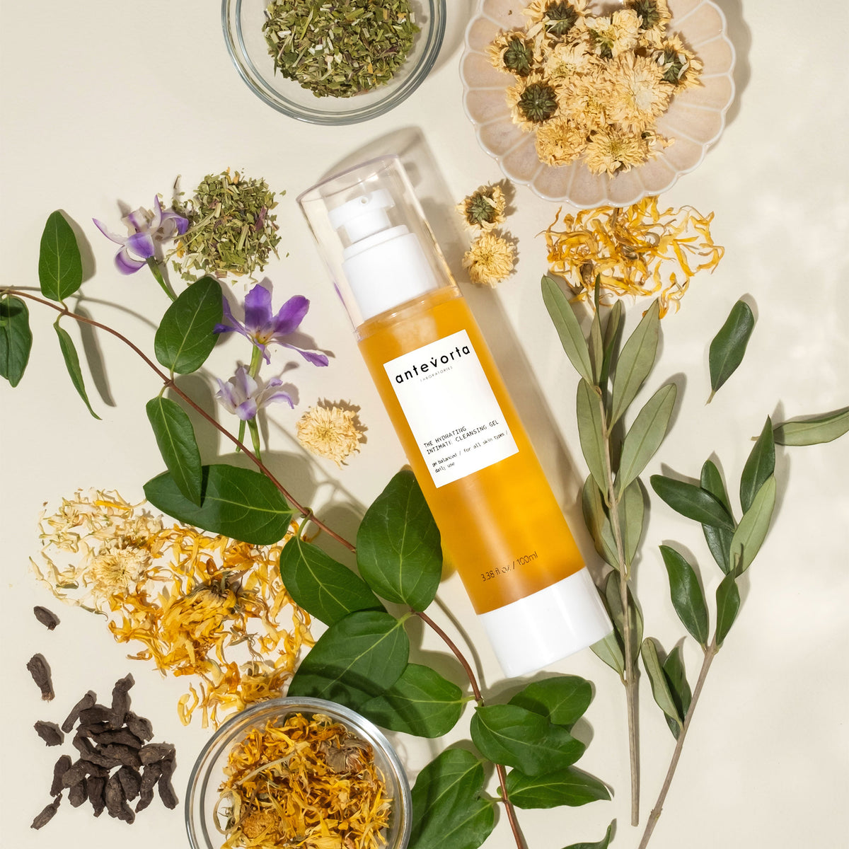 Yellow bottle surrounded by leaves and dry flowers on a beige background