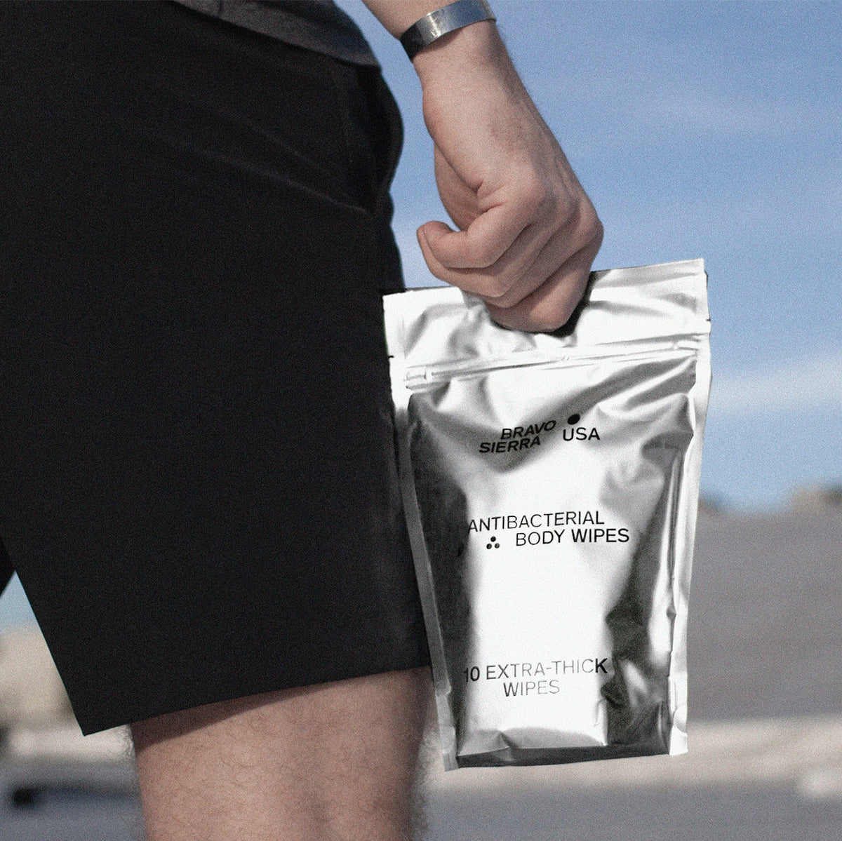 Person holding bag of Bravo Sierra Antibacterial Body Wipes. 