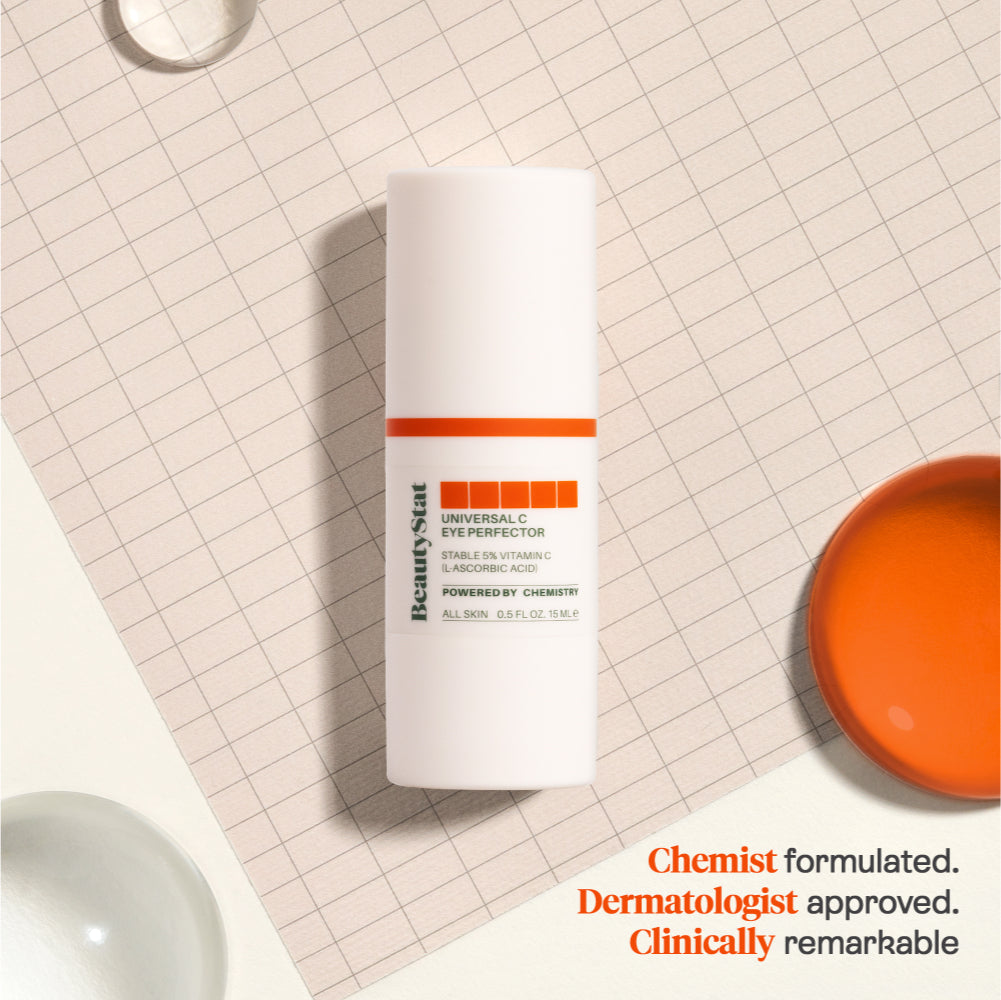 BeautyStat's Universal C Eye Perfector on a gridded background next to droplets of liquid