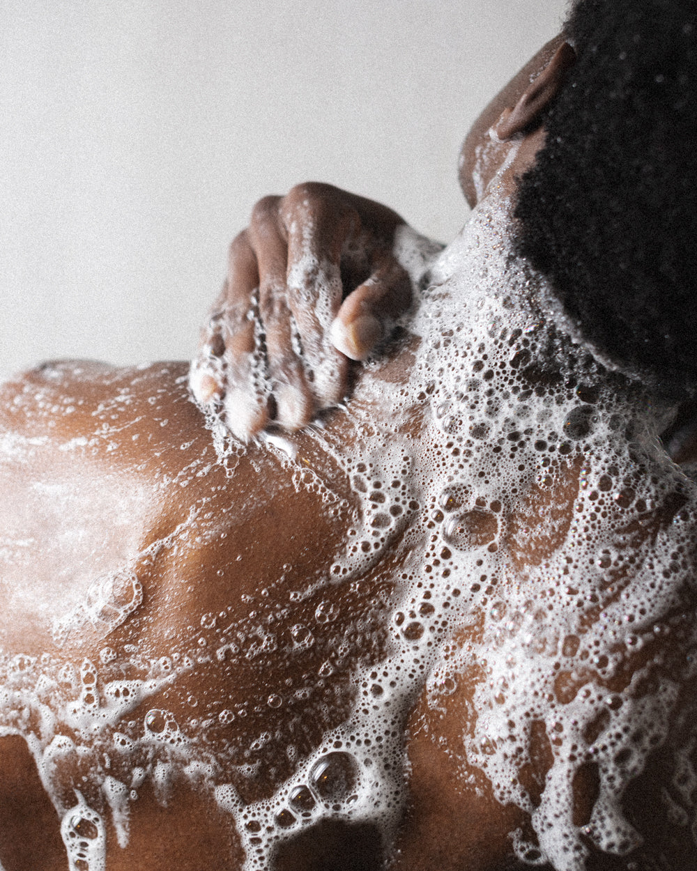 Person applying Bravo Sierra body wash to their soapy back. 