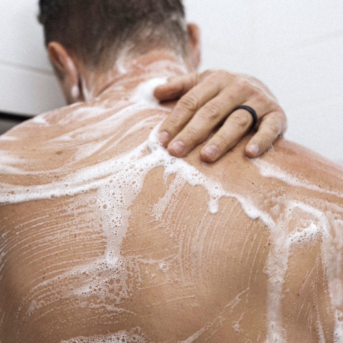 Man washing his soapy back with Bravo Sierra Body wash.