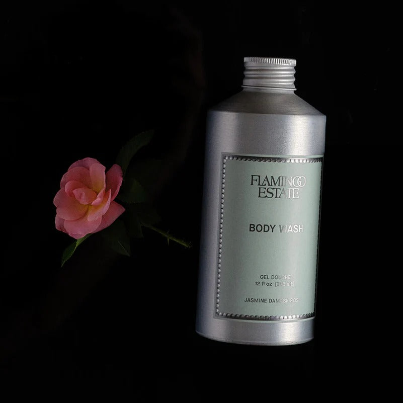 Flamingo Estate body wash bottle with a pink flower on a black background