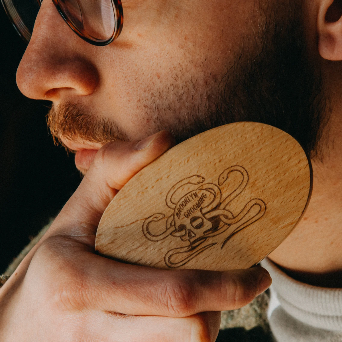 Man holding a wooden brush with a logo, close-up of face and brush.
