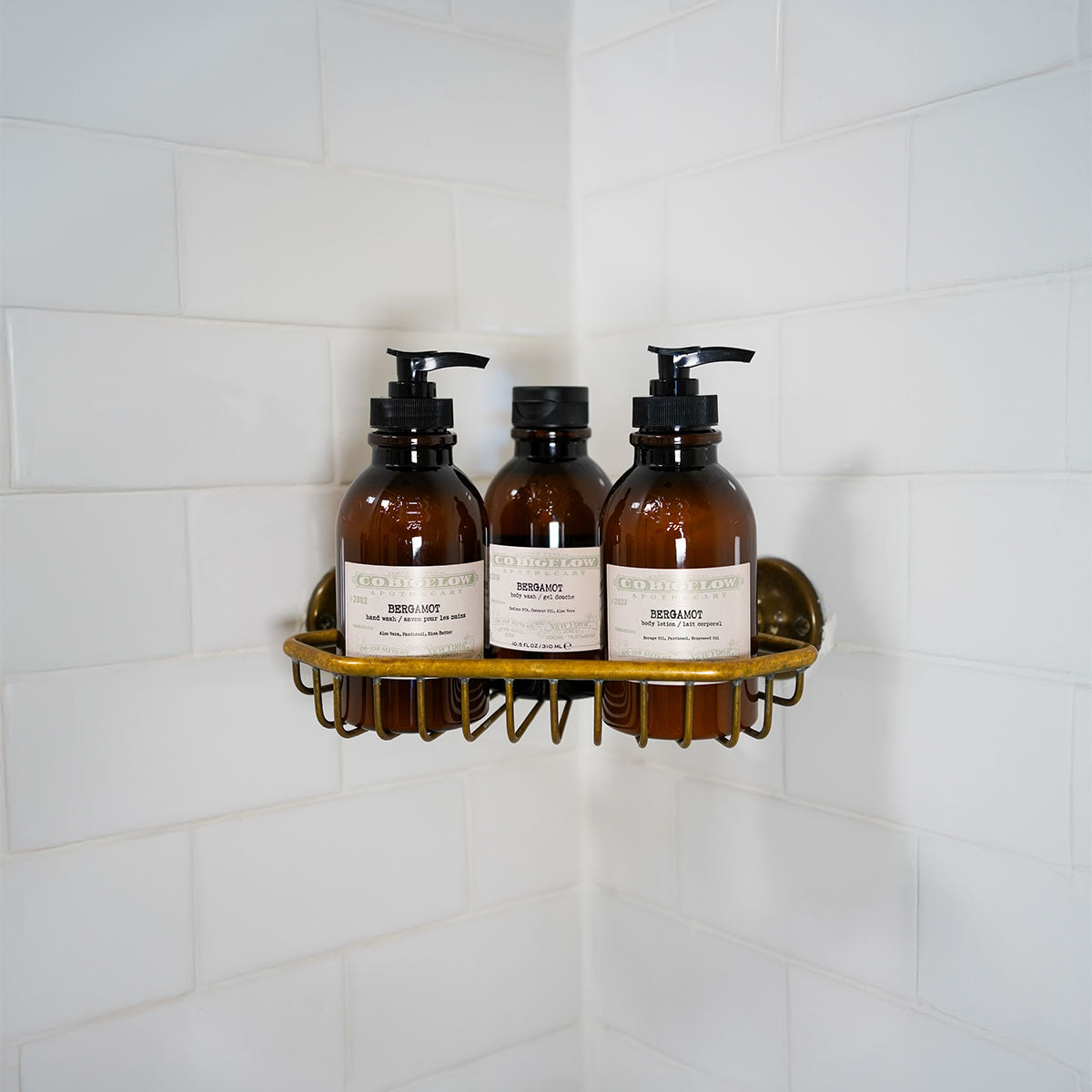 C.O. Bigelow Bergamot Body Lotion, Body Wash, and Hand Wash on a brass shelf in a bathroom shower. 