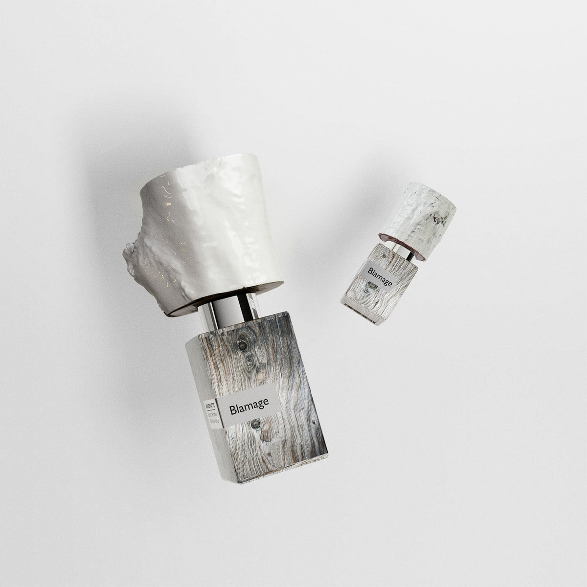 Two silver and wooden perfume bottles with 'Blamage' branding on a light gray background