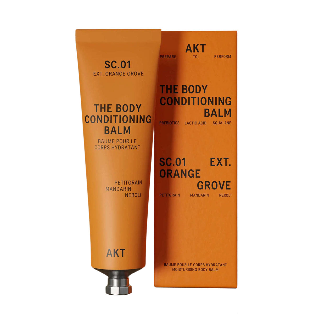 AKT's Orange Grove Body Conditioning Balm tube to the left of it's orange packaging box in front of a white background.