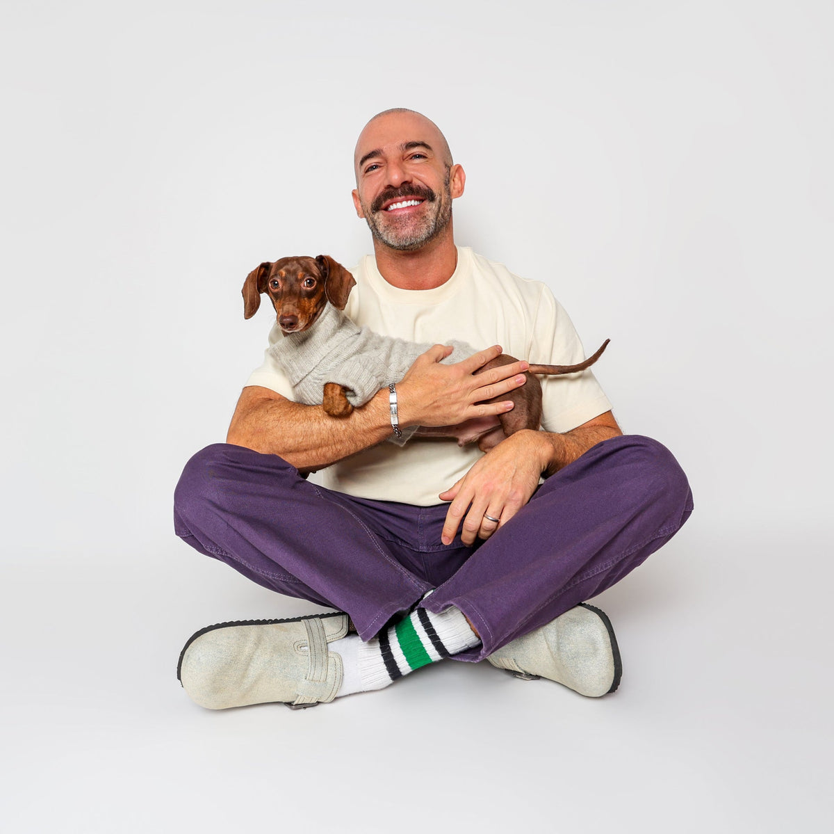 Man holding a dog in front of a white background