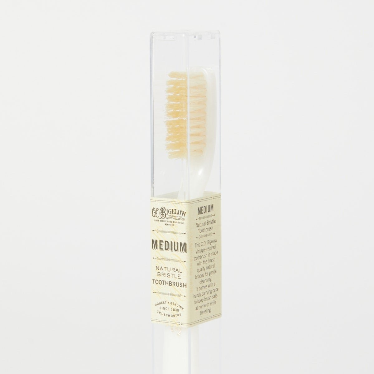 A medium ivory toothbrush with natural bristles, displayed in front of a clear packaging tube.