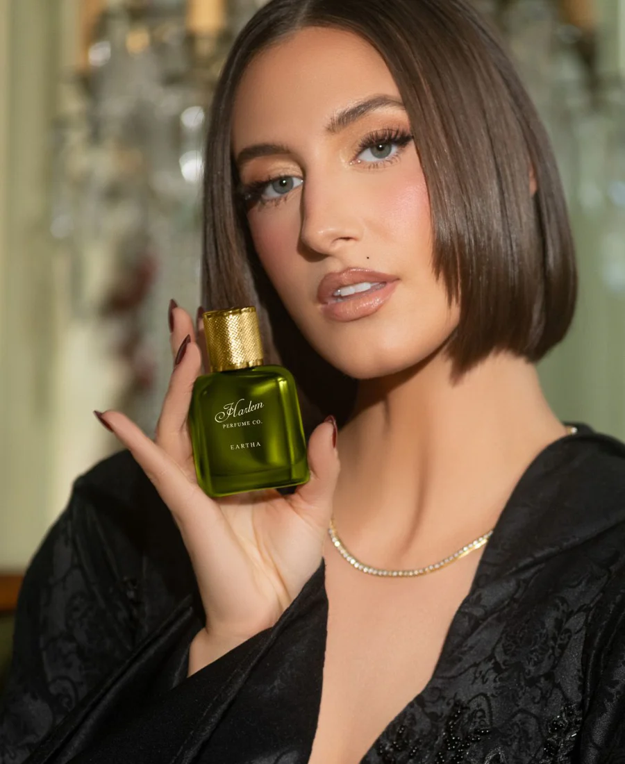 Woman holding a green perfume bottle with a blurred background