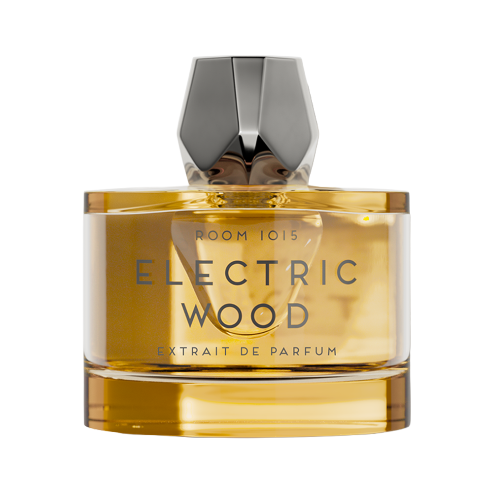 A bottle of Room 1015 Electric Wood Extrait de Parfum, featuring a clear glass bottle filled with amber-colored liquid and a faceted metallic silver cap, set against a plain white background.