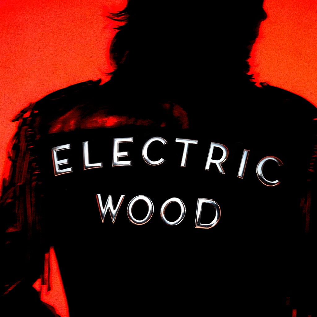 Silhouette of person in a jacket that says ELECTRIC WOOD on the back of it with an orange background