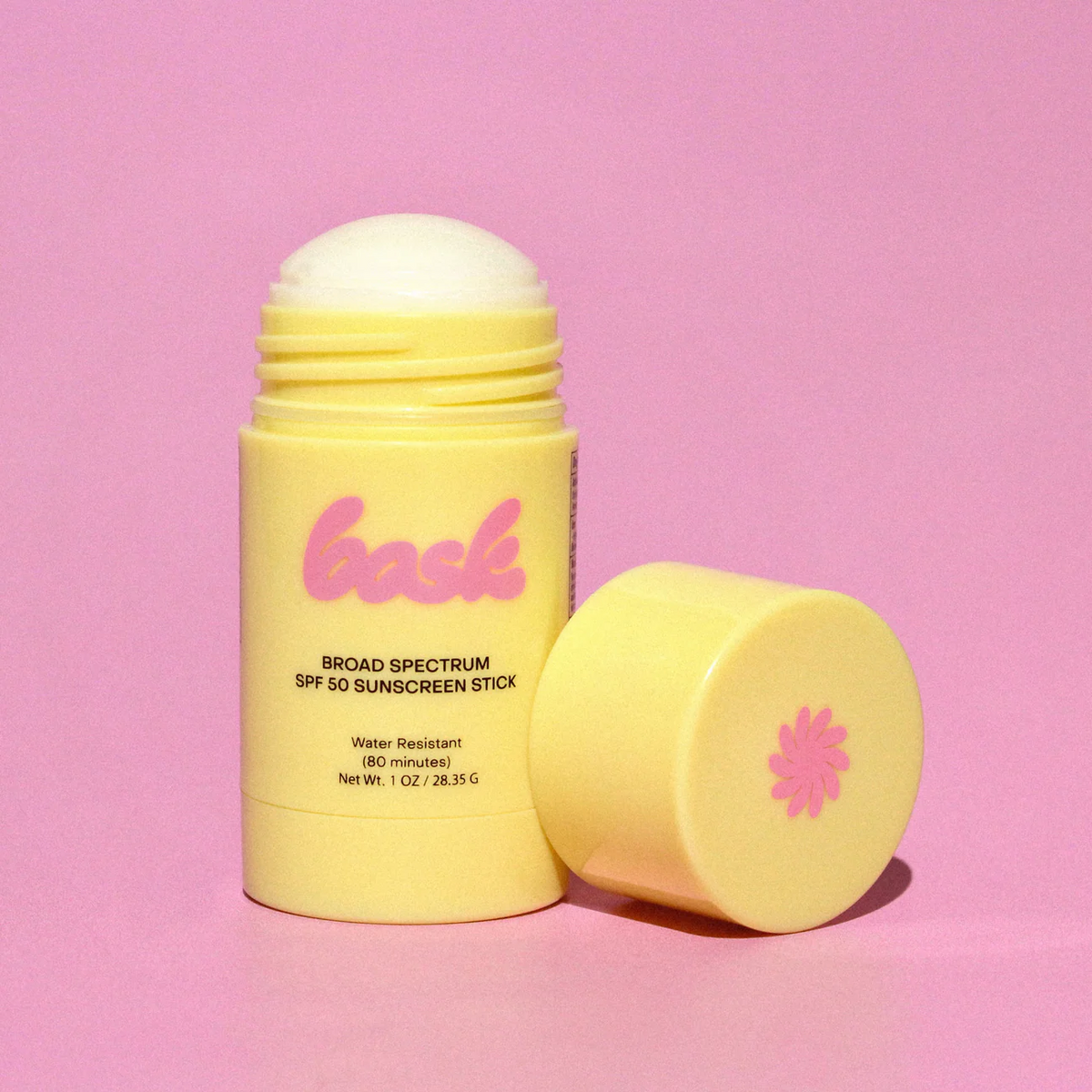 Yellow sunscreen stick with pink logo on a pink background
