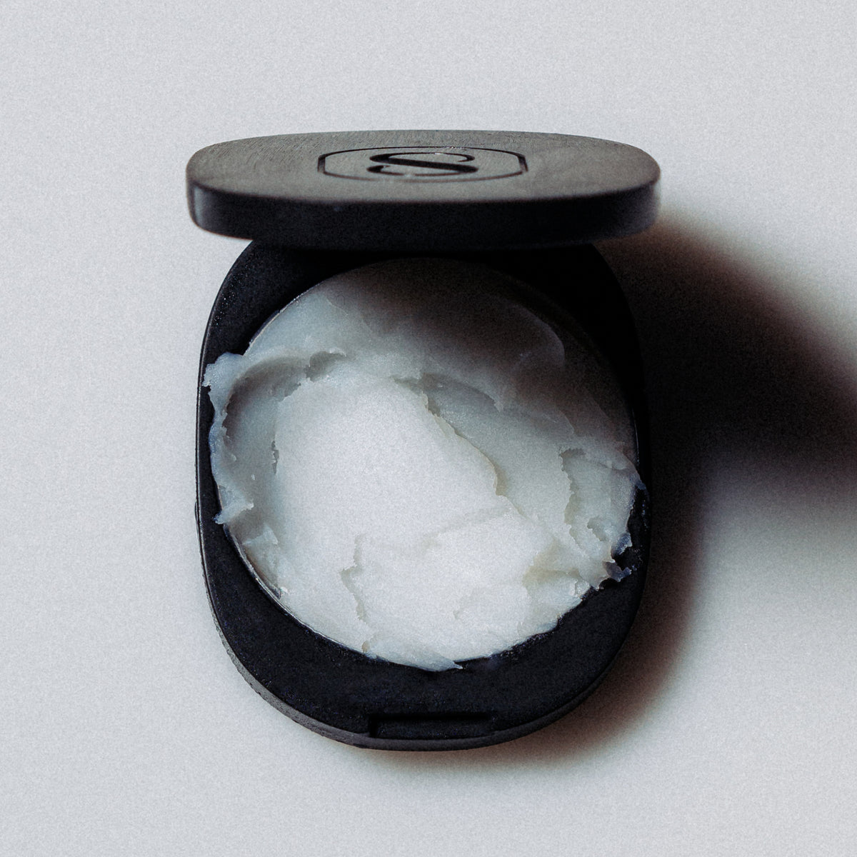 Black container with white cream on a light gray background