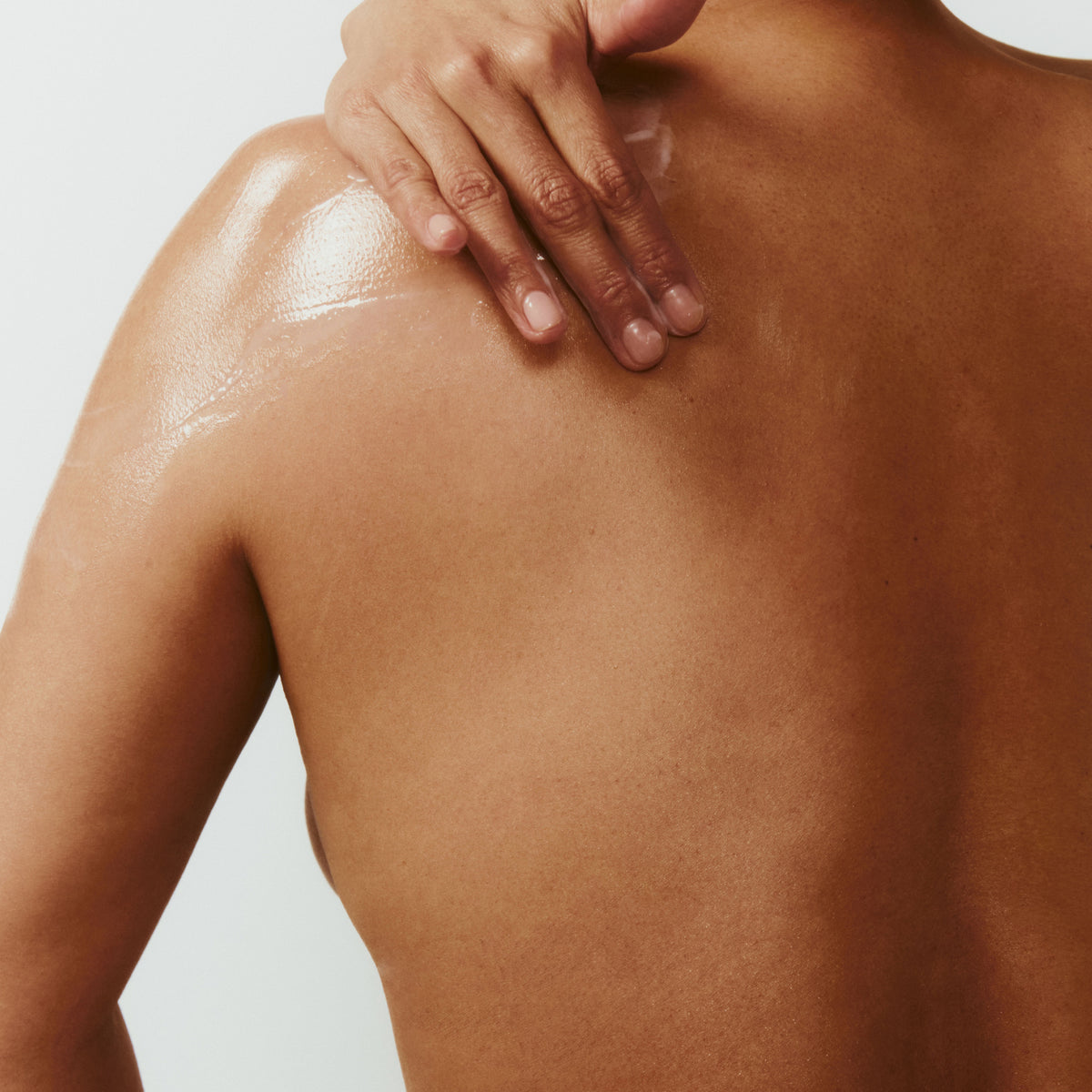 Person applying a body cream to their back
