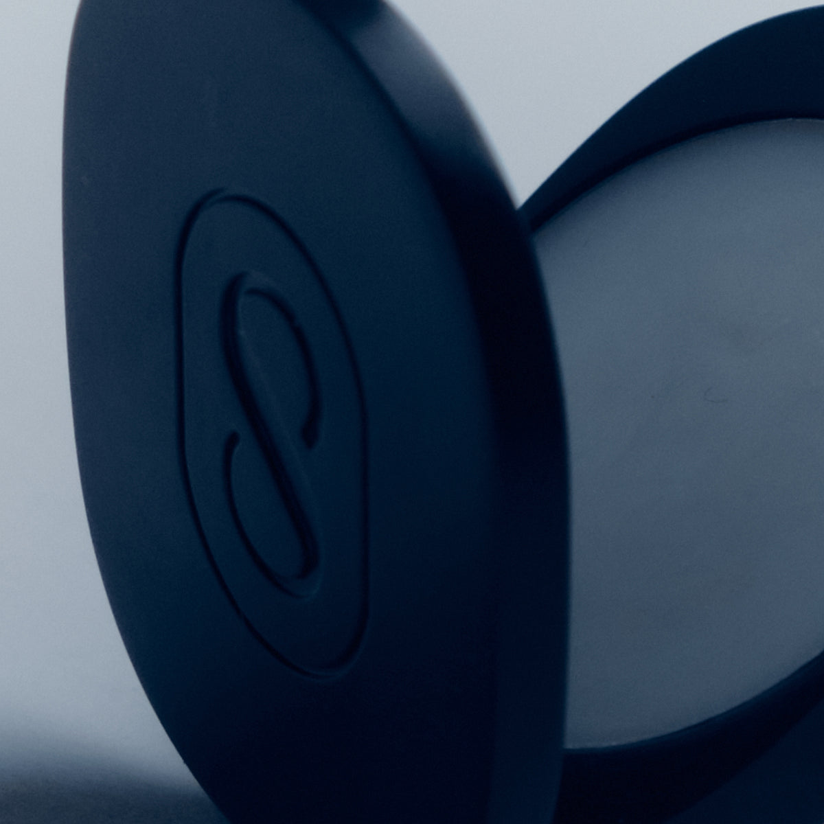 Close-up of a blue earbud with a brand logo on a light gray background